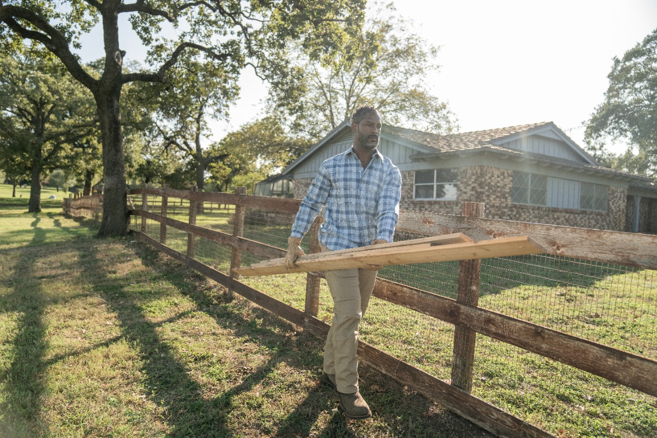 Image of a person carrying rails for a split board fence.