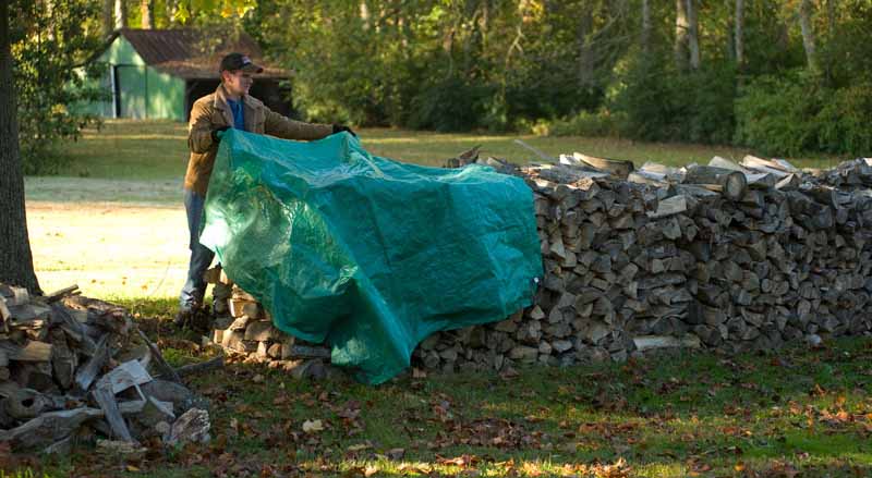 Man covering firewood with a tarp