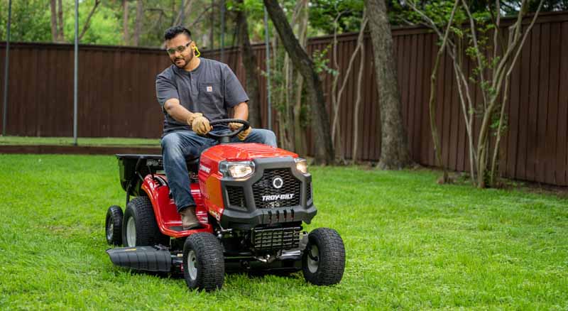 Person using riding mower to cut grass