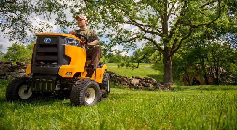 Person using yellow riding mower to cut grass