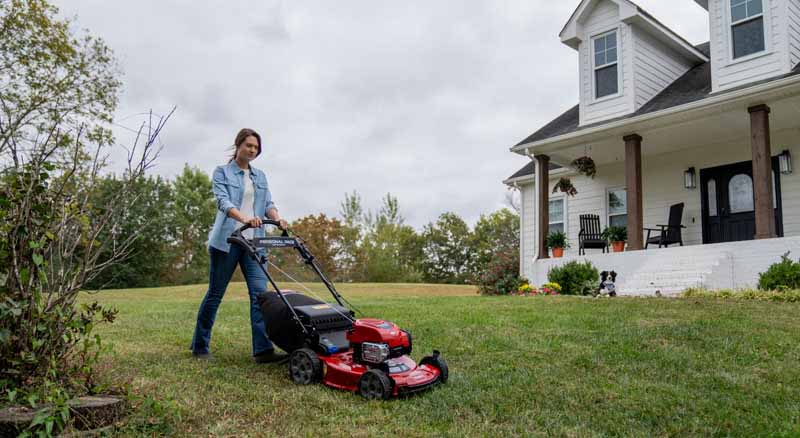 Homeowner cutting lawn with gas mower