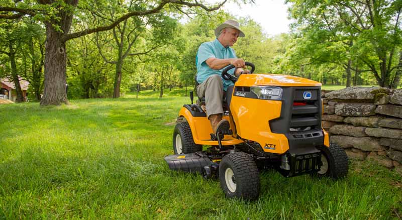 Man mowing grass in front yard of home with Cub Cadet yellow riding mower 